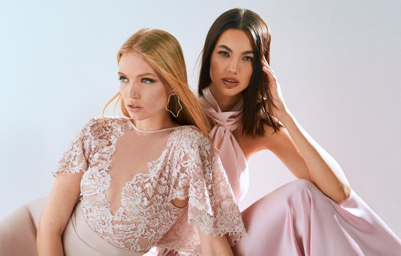 Duas mulheres a usar vestidos de festa em tons de rosa com detalhes rendados