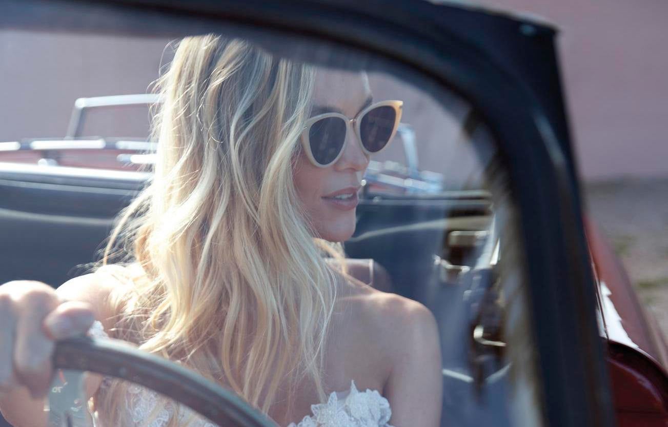 Güneş gözlüğü takarak araba kullanan açık dalgalı saç modeline sahip gelin