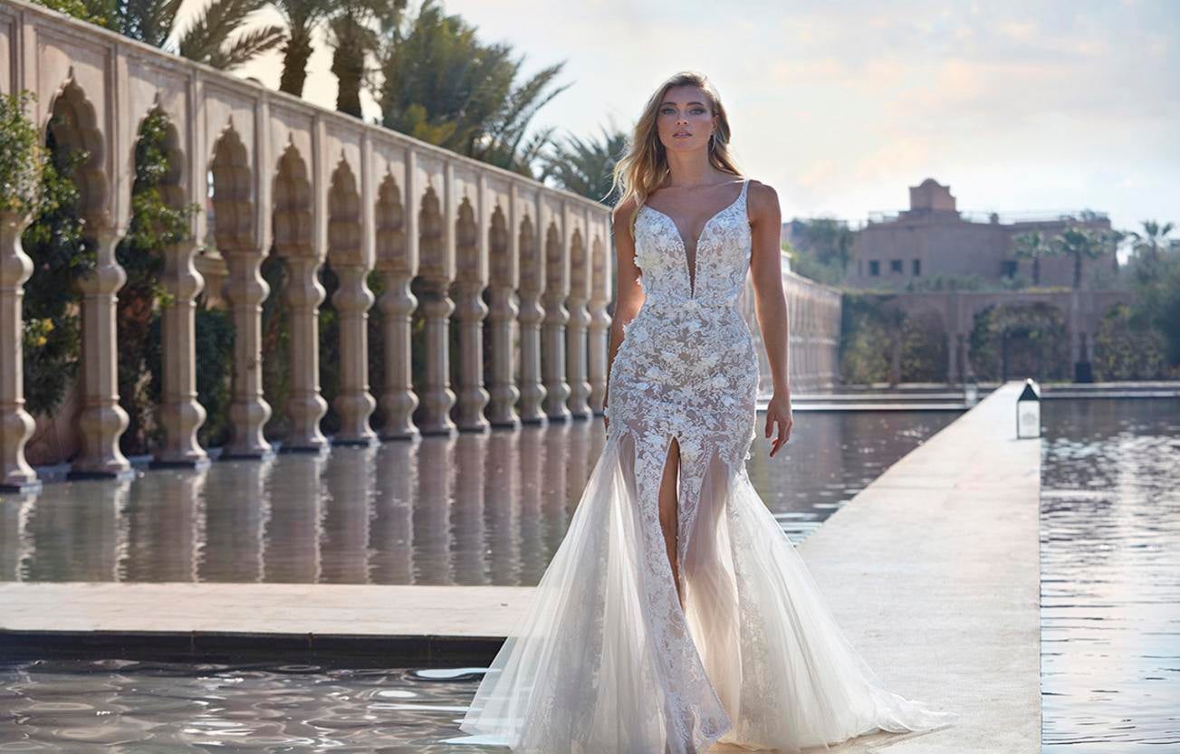 La mariée vêtue d'une robe de mariée transparente à fines bretelles et au décolleté plongeant orné de délicats motifs.