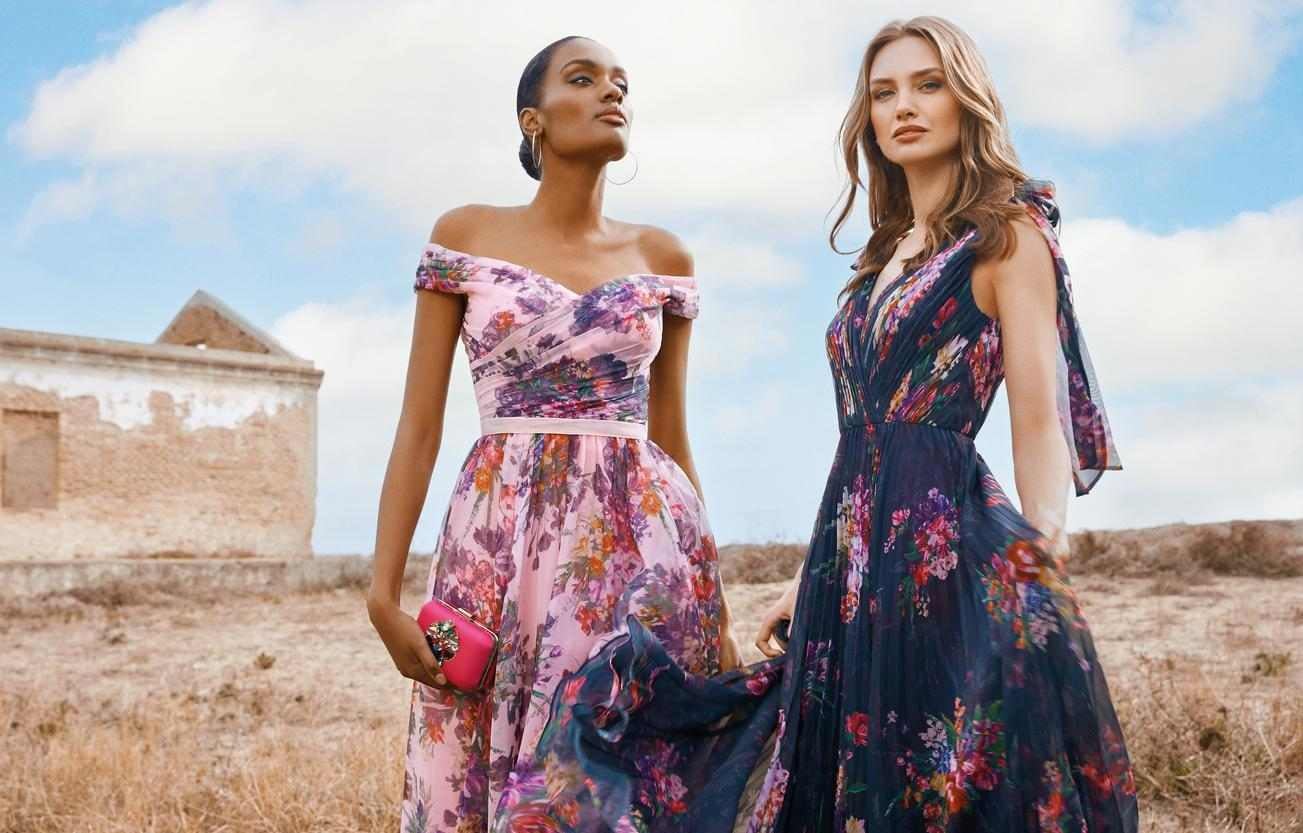 Dwie kobiety w plenerze stojące obok siebie prezentujące kwieciste sukienki na wieczór panieński