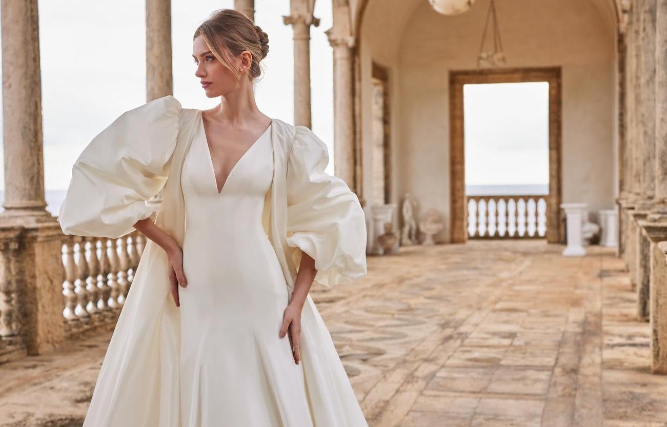 Panna młoda w sukni ślubne w stylu księżniczki odziana w płaszcz ślubny patrząca w oddal