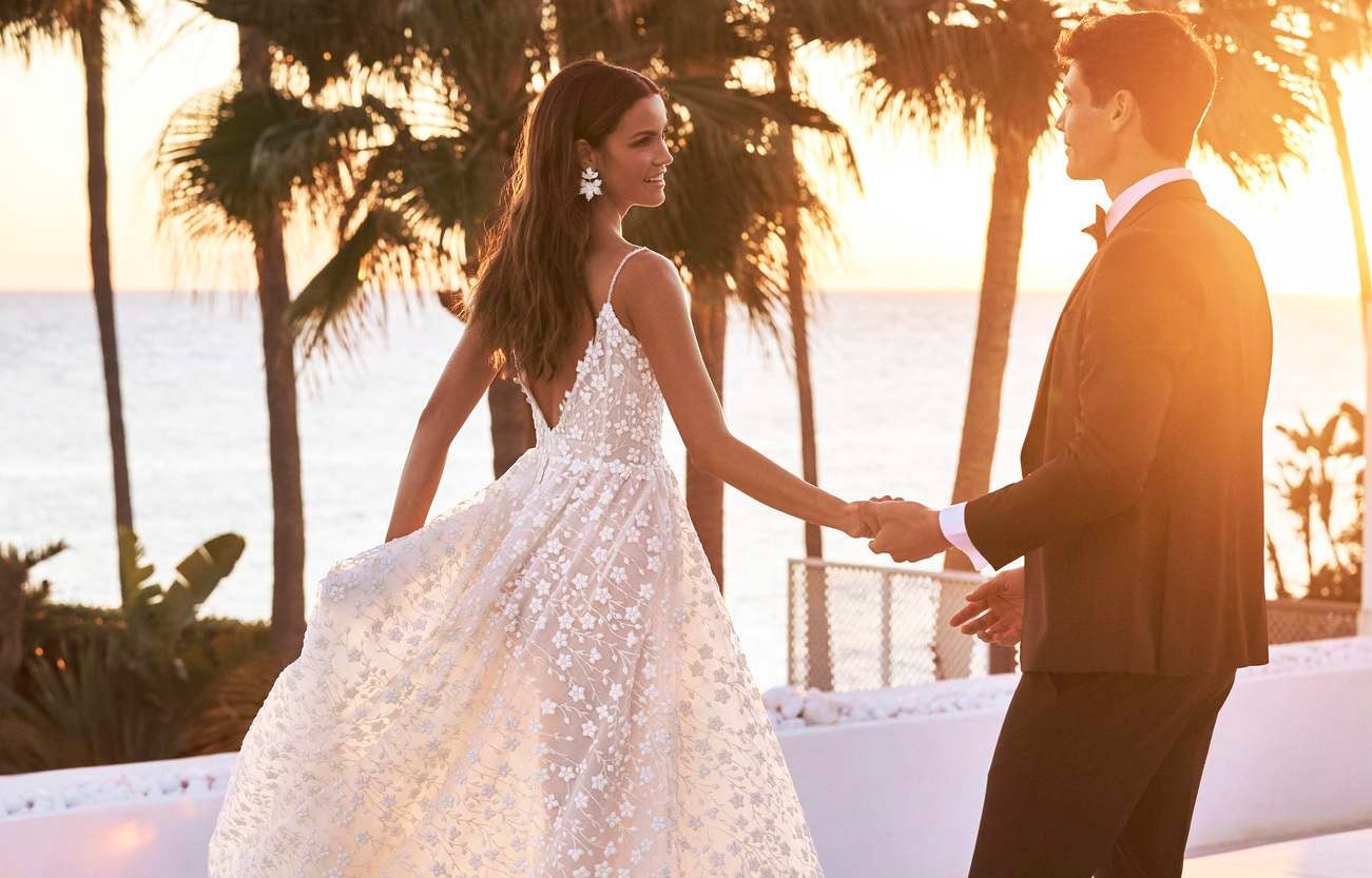 Pan młody w garniturze oraz panna młoda w kwiecistej sukni ślubnej podczas pierwszego tańca 