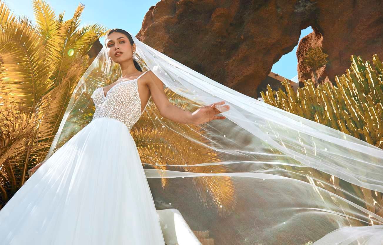 Panna młoda w sukni ślubnej typu księżniczka trzymająca długim rozwiany welon