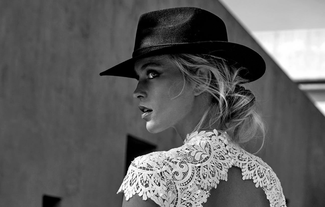 Mujer con un sombrero y un vestido de novia tradicional mirando hacia un lado
