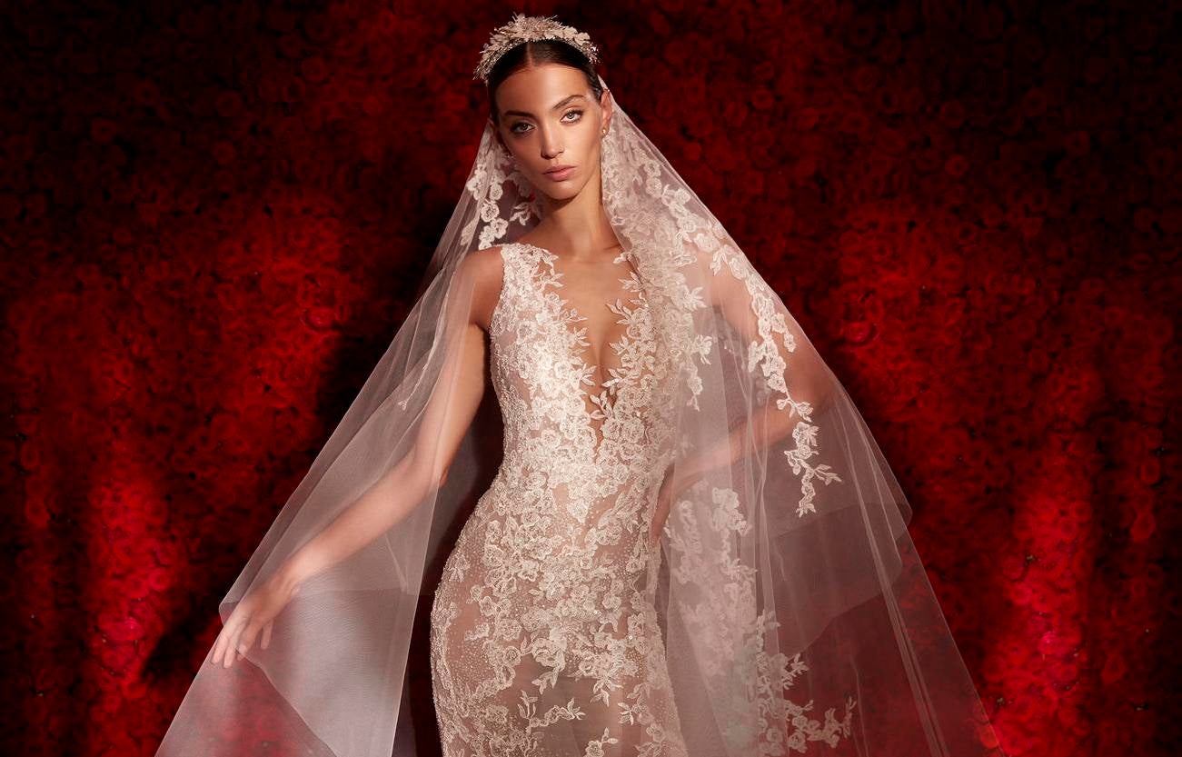 Modella in primo piano che indossa un abito da sposa e un lungo velo in tulle ricamato.