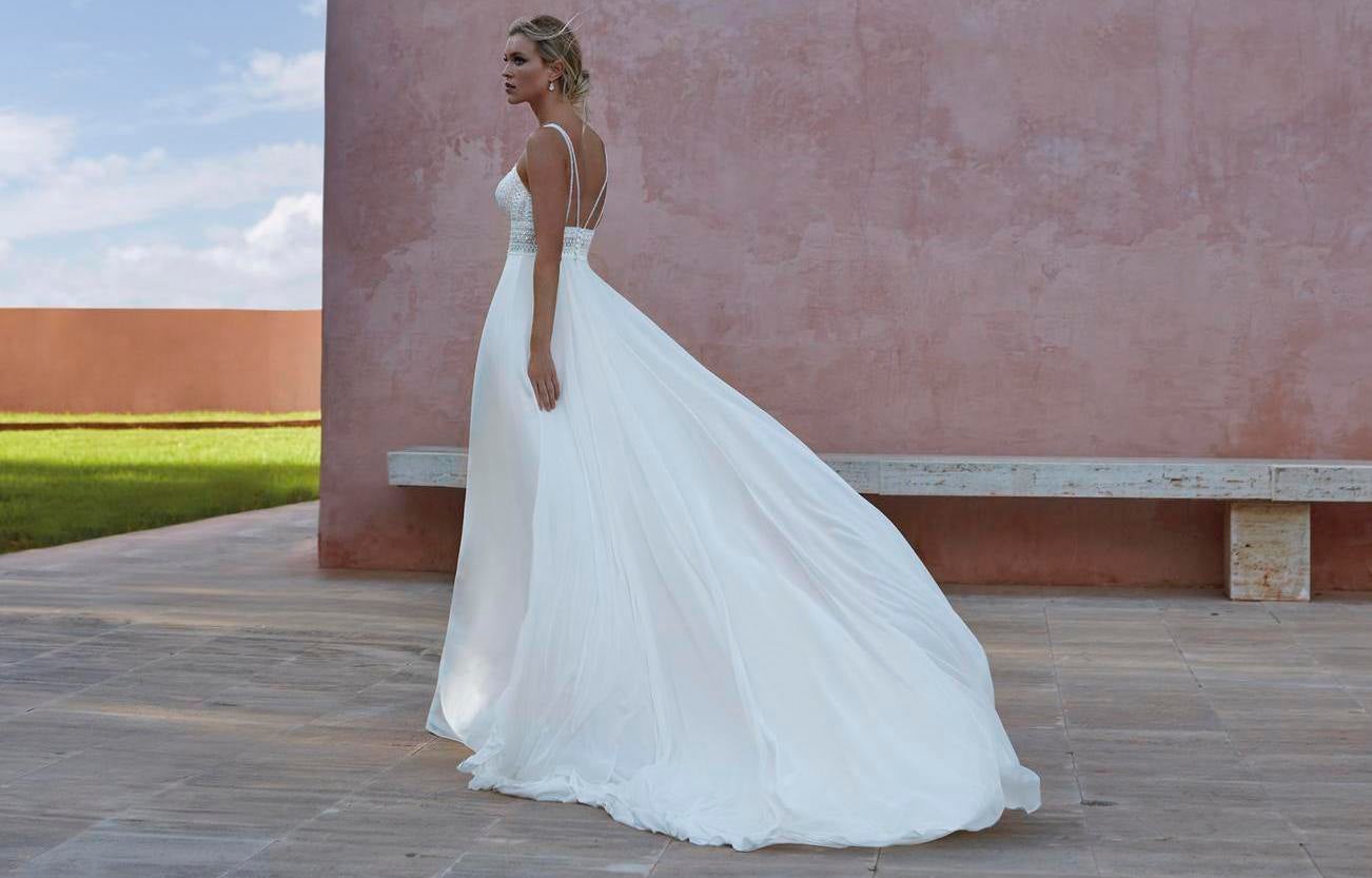 Donna di schiena con abito da spoosa scivolato, strascico lungo e schiena scoperta.