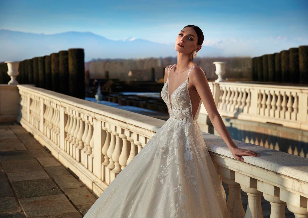 Modelo usa vestido de noiva evasé com flores aplicadas e decote V, estilo vintage, sem mangas com brincos e penteado preso