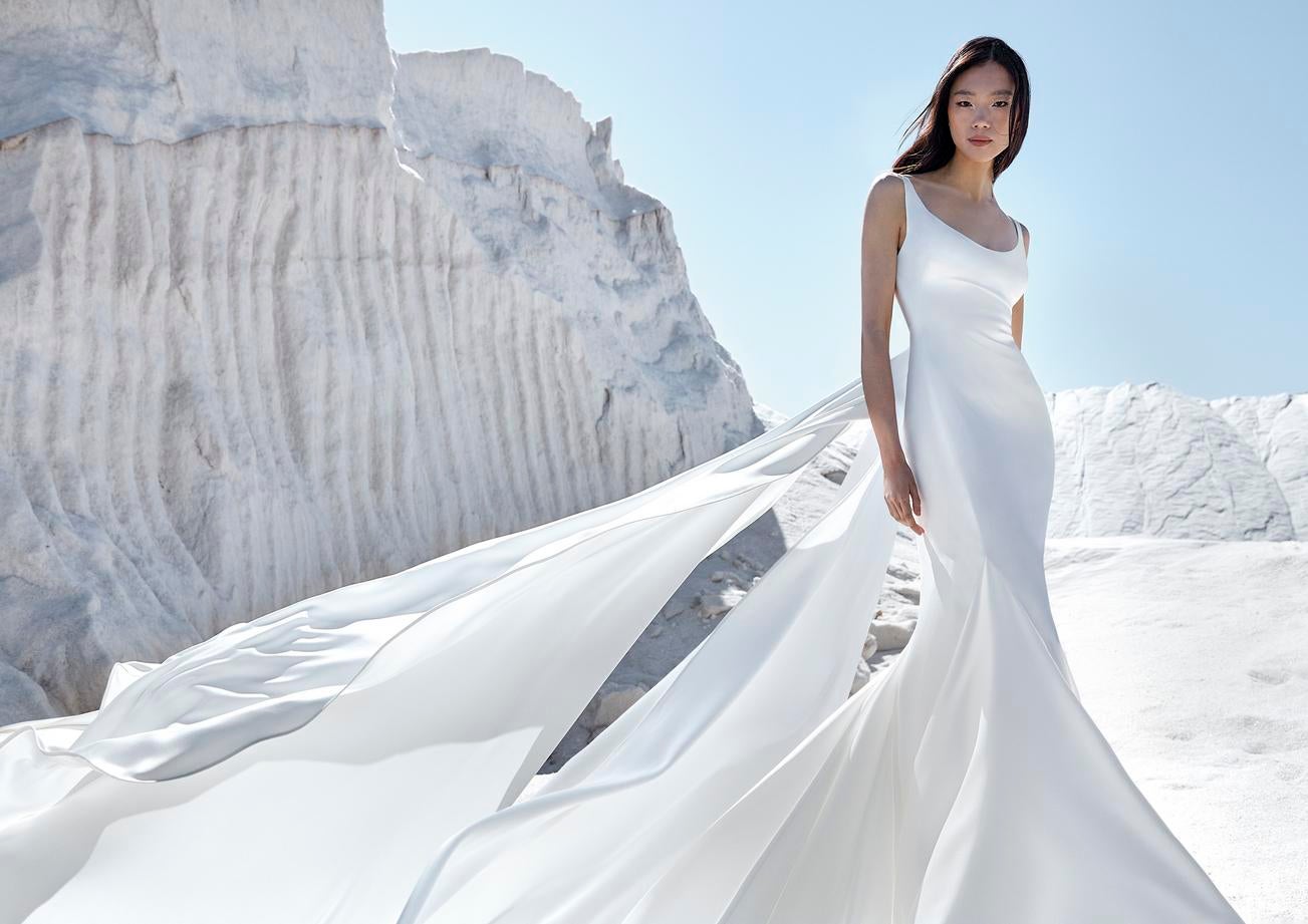 Εντυπωσιακή γυναίκα που φοράει μίνιμαλ λευκό νυφικό που ανεμίζει