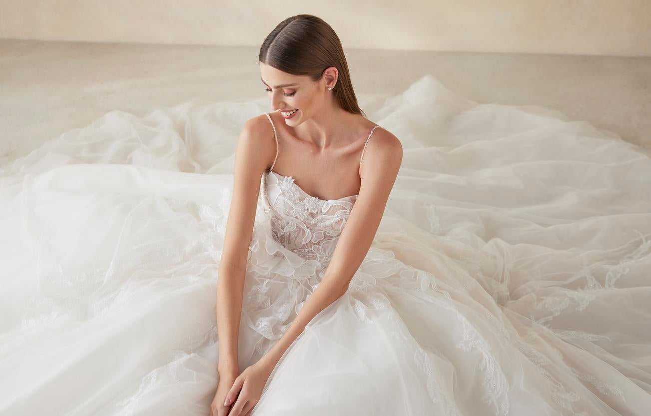 Χαμογελαστή νύφη που κάθετε περιτριγυρισμένη από την φουσκωτή φούστα του εντυπωσιακού νυφικού της