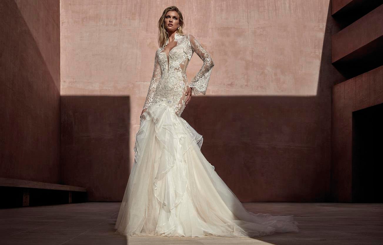 Noiva posa com vestido de casamento com babado na saia, corte sereia de renda com decote V, mangas longas e penteado simples cabelos soltos