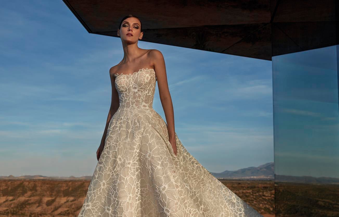 Woman wearing a sleeveless A-line wedding dress with a sweetheart neckline, standing outside