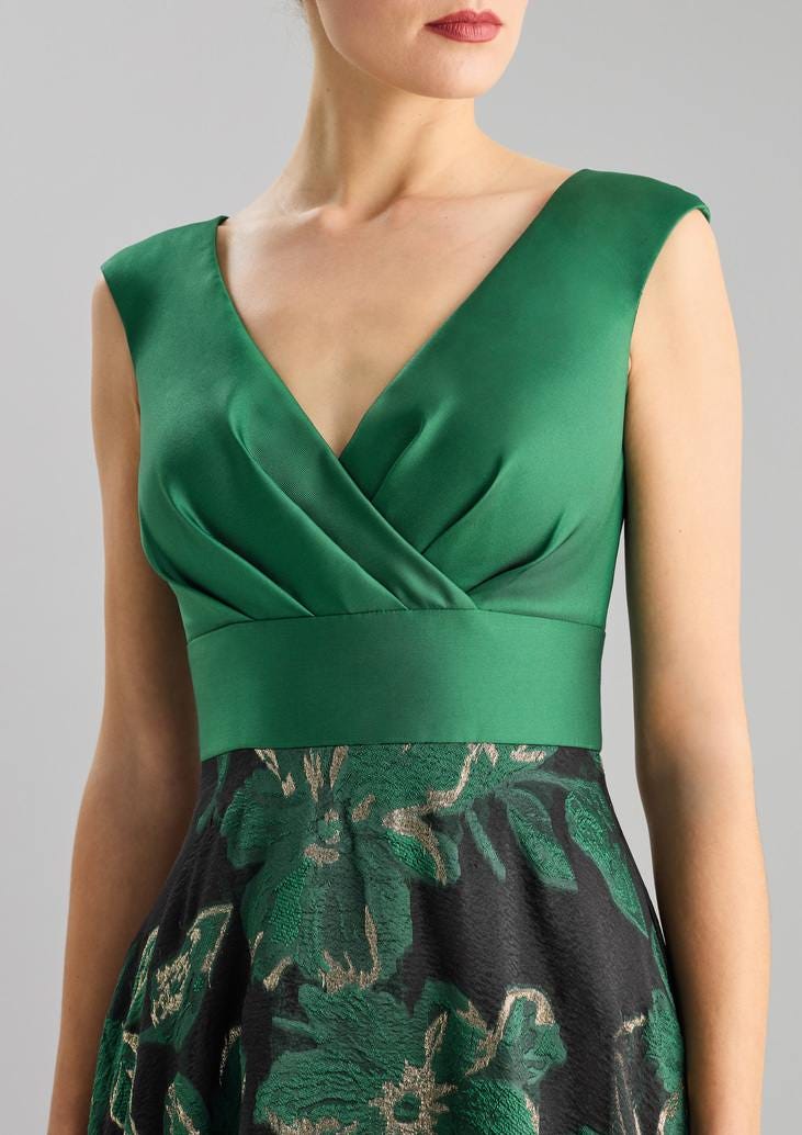 Frau in grünem Seidenabendkleid mit Blumenmuster unterhalb der Taille