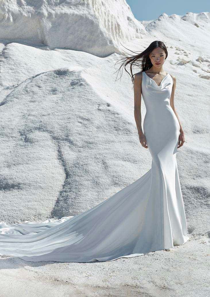 Mujer en un una monta&ntilde;a blanca con un vestido de novia color blanco con corte sirena