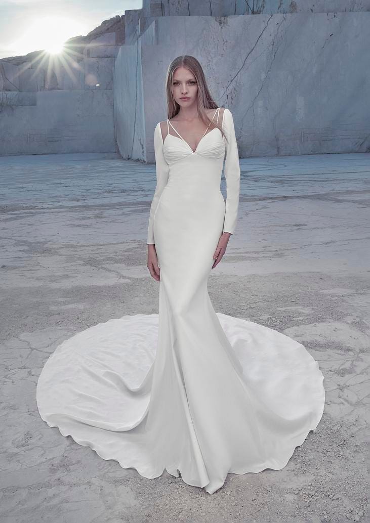 Robe de mariée en satin à manches longues Une jeune femme porte une robe de mariée en satin avec de longues manches, symbole d'élégance et de raffinement.