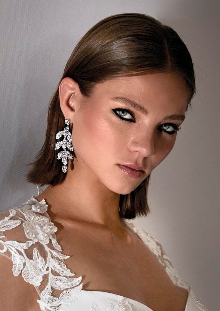 Braut mit kurzem Haarschnitt mit Glitzerohrringen und markantem Augen Make up