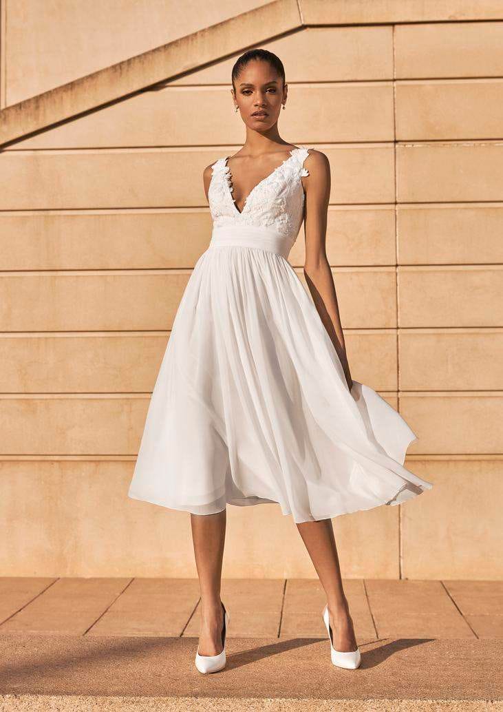 Vestido de novia escote en V Mujer luciendo un vestido de novia con escote en V y llevando unos zapatos elegantes de novia