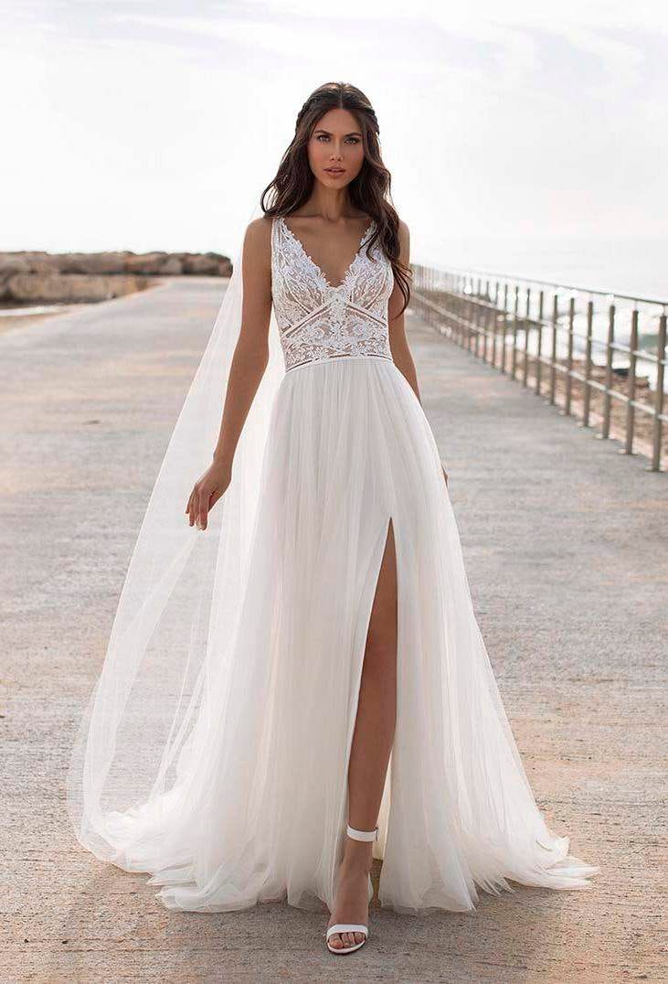 Une &eacute;l&eacute;gante mari&eacute;e v&ecirc;tue d'une robe de mari&eacute;e boh&egrave;me avec des d&eacute;tails en dentelle sur le buste et une jupe fluide fendue.