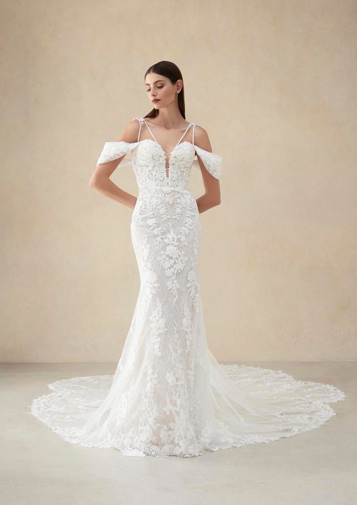 Donna con abito da sposa a sirena in pizzo con spalline fine, maniche laterali e spalle scoperte