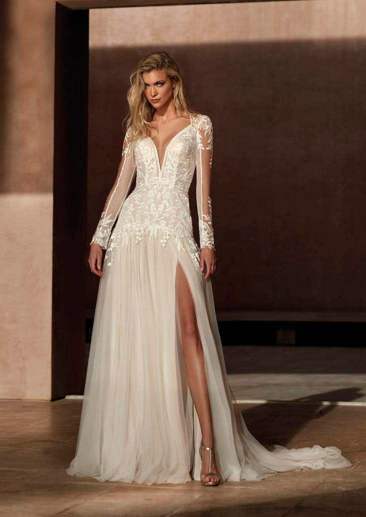 Donna con vestito da sposa in tulle e pizzo con scollo a V, maniche lunghe ricamate e spacco laterale sul davanti