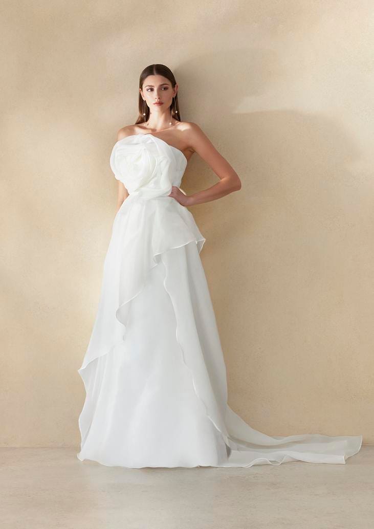 Noiva usando um vestido branco de linha A, onde se destaca o formato de flor na zona do busto