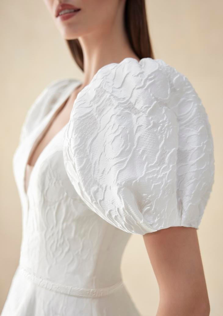 Wedding dress with puffy sleeves Dark-haired woman wearing a V-neck lace wedding dress with short, puffy sleeves.