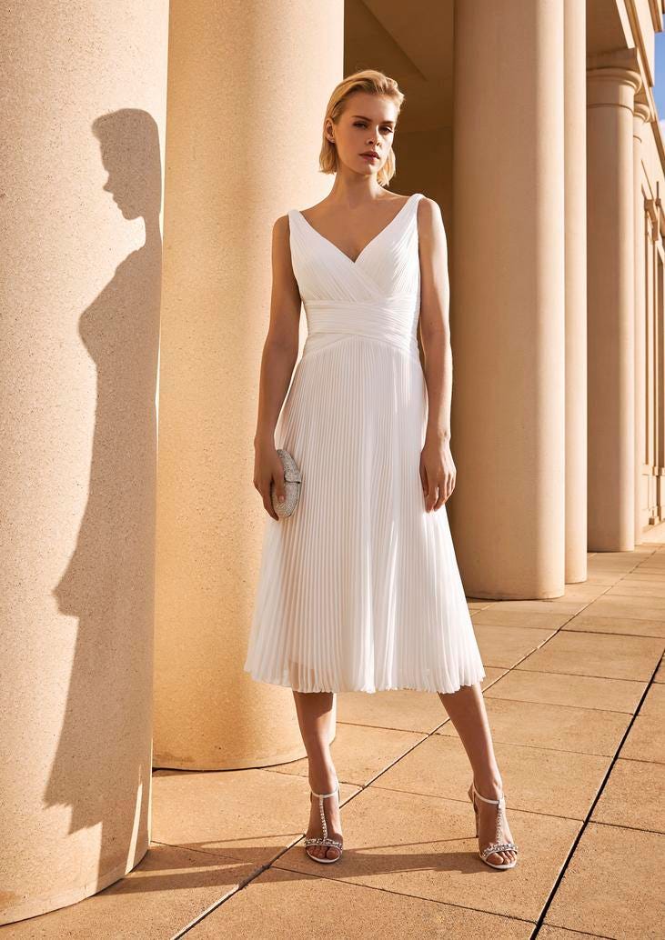 Noiva com cabelo solto, vestido simples plissado corte A midi e com acessórios brincos, sandálias e clutch