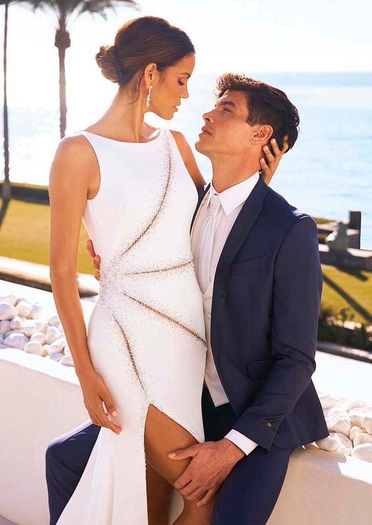 Un couple v&ecirc;tu de tenues de mariage. La femme porte une somptueuse robe de mari&eacute;e droite et l'homme un costume luxueux