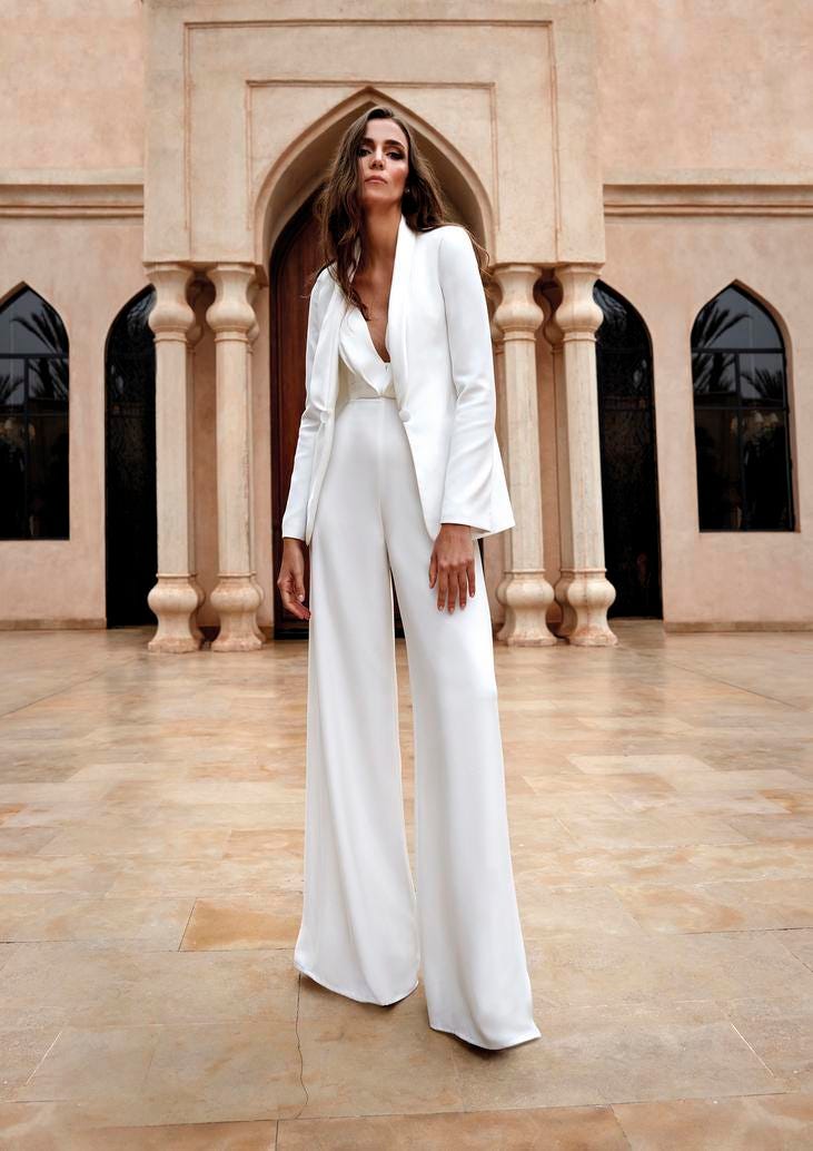 Modella che indossa un elegante abito da sposa con giacca, pantalone e scollatura a V.