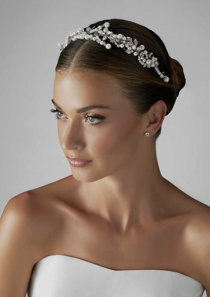 Noiva a usar uma maquilhagem leve conjugado com um penteado simples com coque baixo e uma tiara