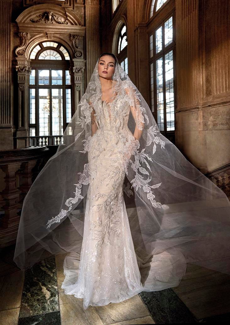 Mujer luciendo un vestido de novia de princesa real con corte sirena con un velo largo y el pelo recogido