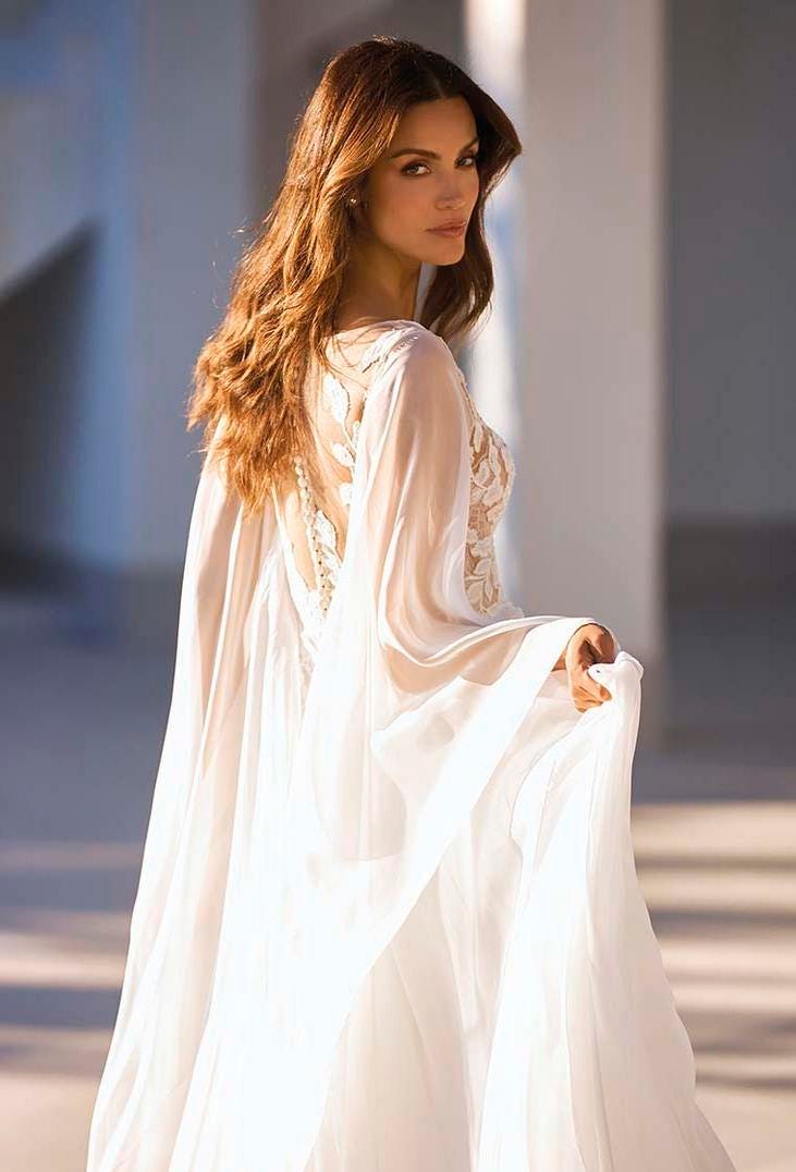 Une mari&eacute;e &eacute;l&eacute;gante dans une robe de mari&eacute;e blanche &agrave; motif en dentelle munie d'une cape amovible.