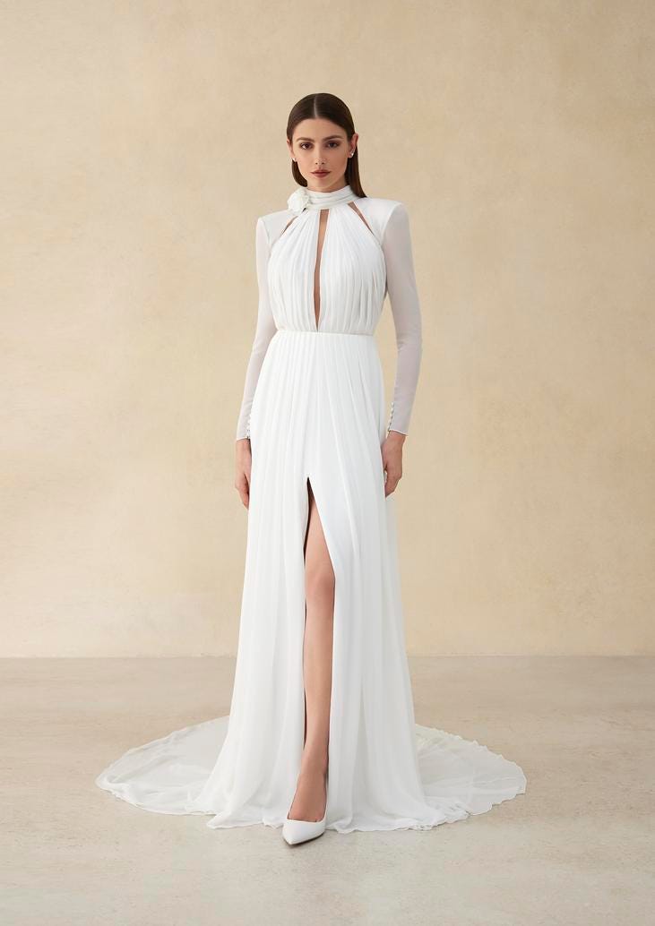 Kobieta w pozycji stojącej w długiej zabudowanej sukni ślubnej z długimi rękawami