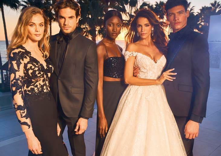 Panna młoda w białej sukience oraz pan młody wraz z gośćmi weselnymi ubrani w czarne kreacje