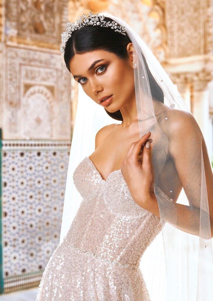 Braut in schulterfreiem Glitzerkleid mit langem Schleier und glitzerndem Haarschmuck 