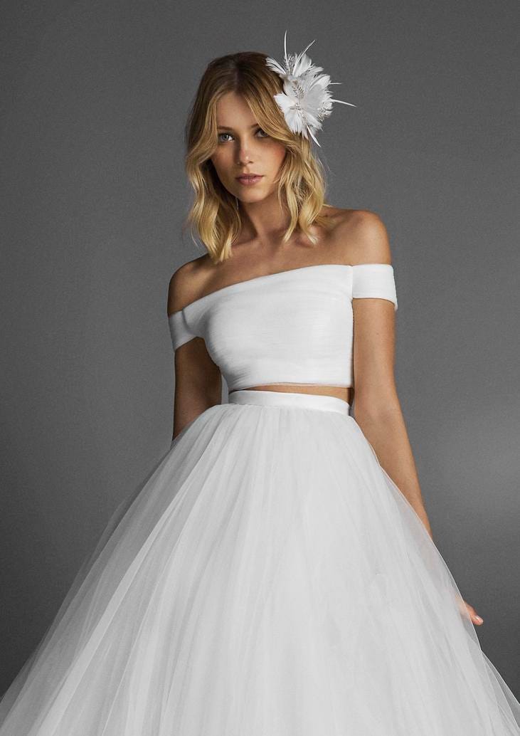 Noiva usando um vestido de tule conjugado com um penteado de ondas suaves e um toucado com penas