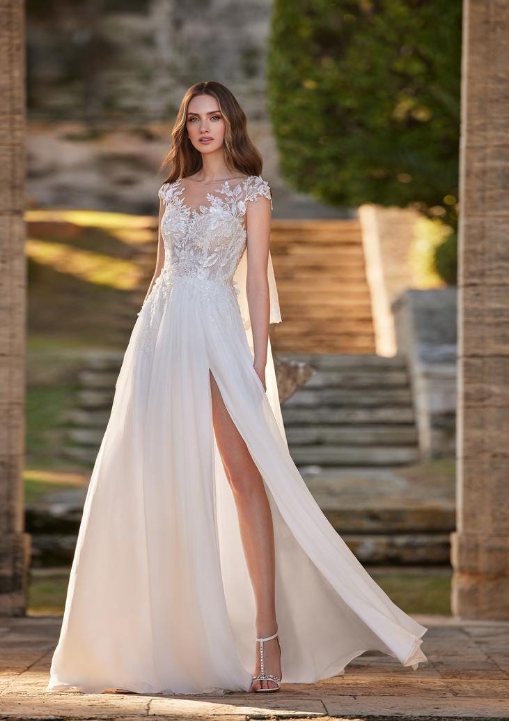 A&ccedil;ık alanda dantelli v yaka ve yırtma&ccedil;lı gelinlik giyerek poz veren gelin