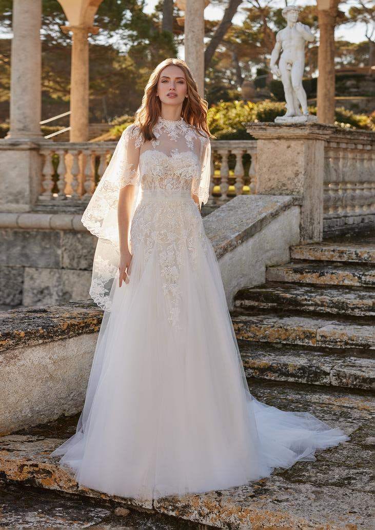 Noiva de cabelos louros usando um vestido de tule com apliques rendados conjugado com um casaco