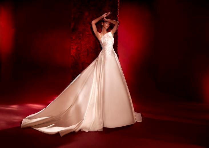 Dark-haired woman in a strapless ball gown wedding dress with hair styled in a high bun.