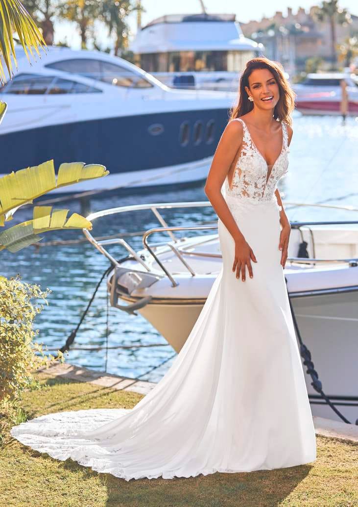 Modella che indossa un lungo abito da sposa boho con scollo a V e strascico ricamato sul bordo