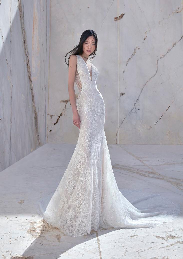 Abito Sposa a Sirena di Pizzo Modella che indossa un elegante vestito da sposa a sirena in pizzo con scollo a V e decorazioni di perline