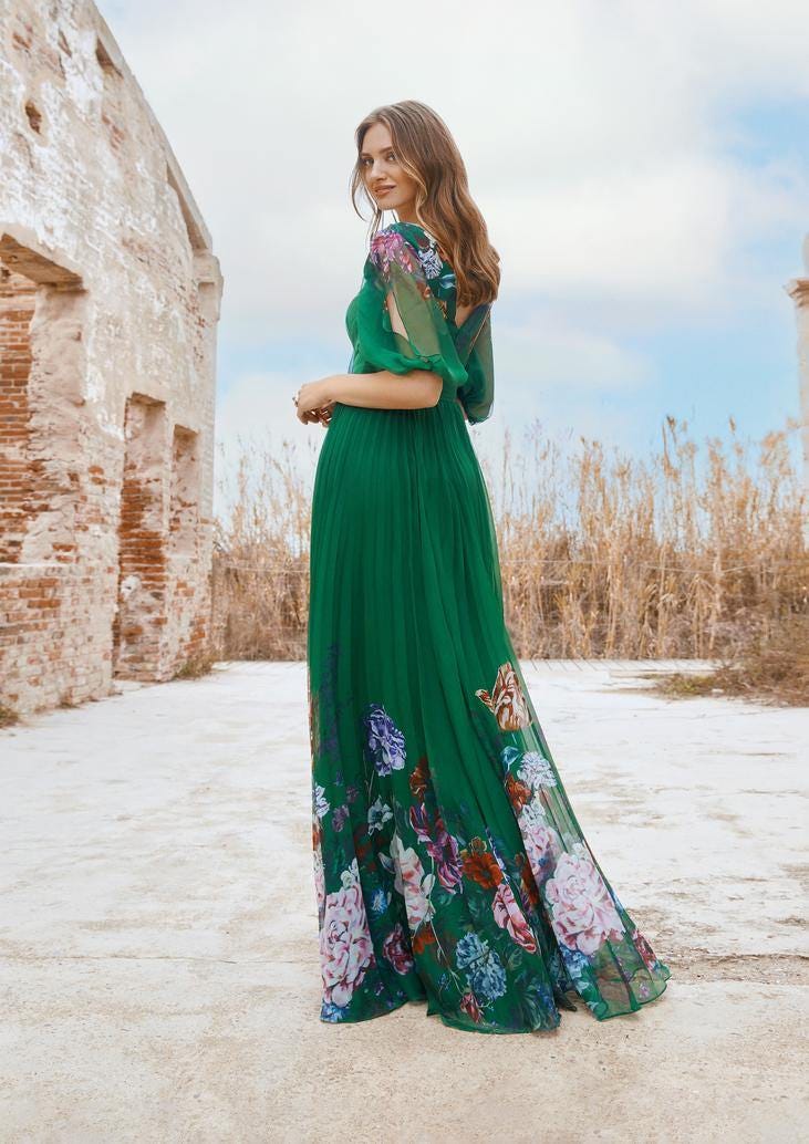 Convidada com vestido de dama de honor verde longo com mangas balão e motivos florais posa com penteado solto simples