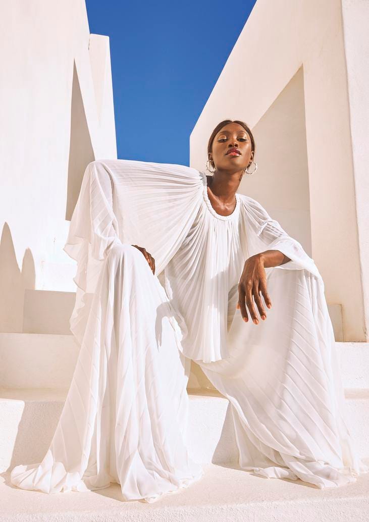 Pantalón y blusa para boda civil Mujer vestida de novia sentada en unas escaleras vistiendo un pantalón y una blusa para una boda civil.