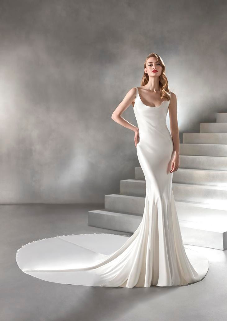 Robe de mariée fluide en satin blanc Jolie jeune femme en robe de mariée fluide et en satin blanc, ornée d'un décolleté profond et d'une traîne arrondie