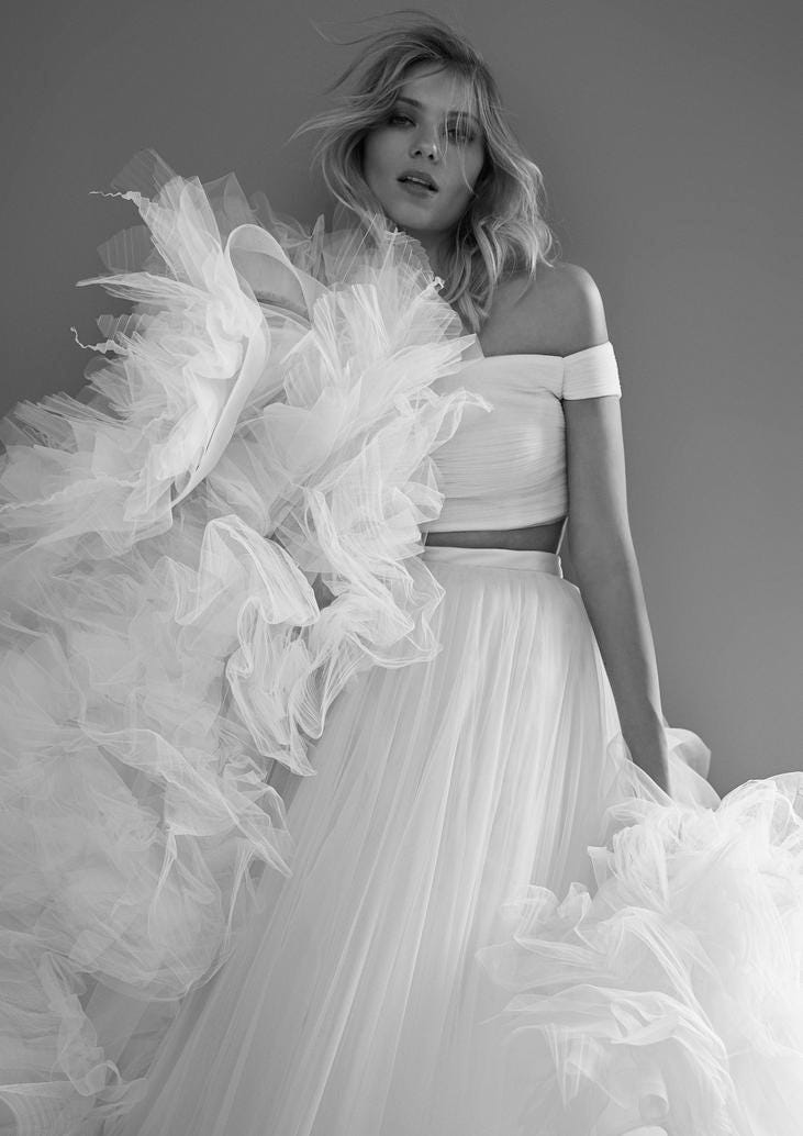 Blonde Frau in weißem Brautzweiteiler aus Tüll und mit Tüll umschwungen