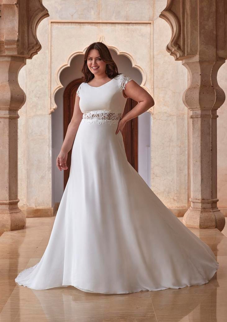 Modella curvy che indossa un abito da sposa semplice plus size a maniche corte.