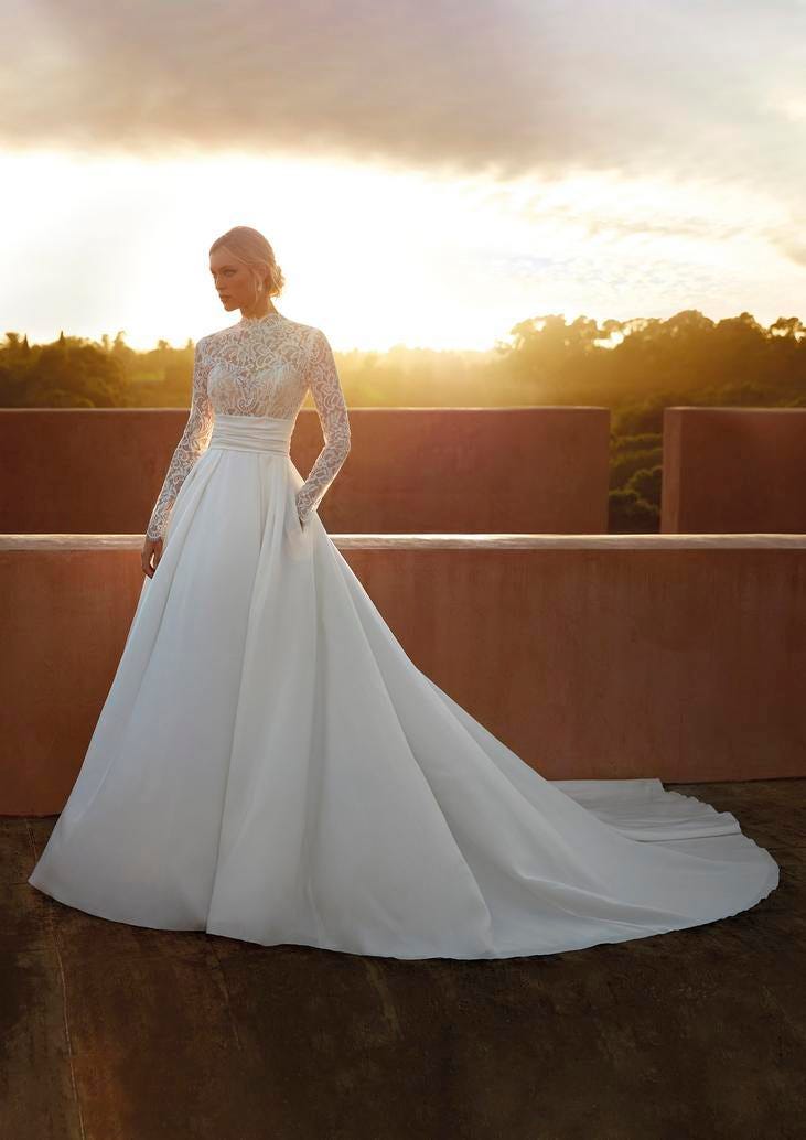 Noiva com vestido corte princesa de manga longa de bordados florais e penteado cabelo apanhado