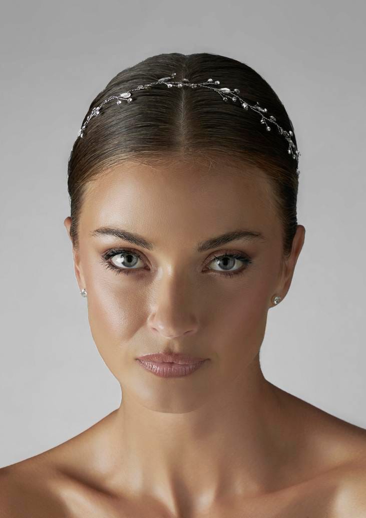 Acessório de noiva de tiara com brilhantes Rosto de noiva com tiara de brilhantes florais e brincos simples com penteado apanhado