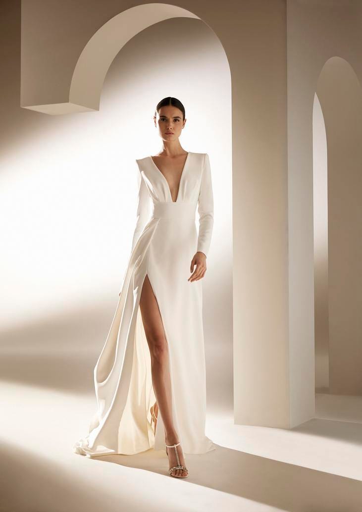 Vestido de noiva longo com fenda e um decote em bico profundo conjugado com um penteado e umas sandálias simples