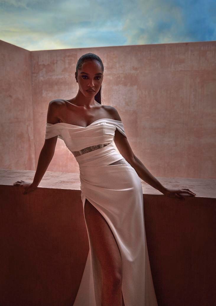 Woman in an off-the-shoulder wedding gown with illusion cut outs and a high slit on the side.