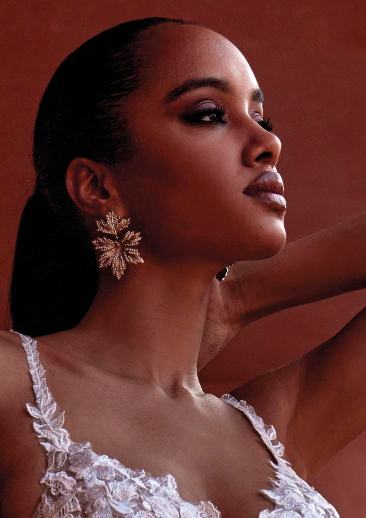 Mujer luciendo unos pendientes de novia dorados con forma de flor 